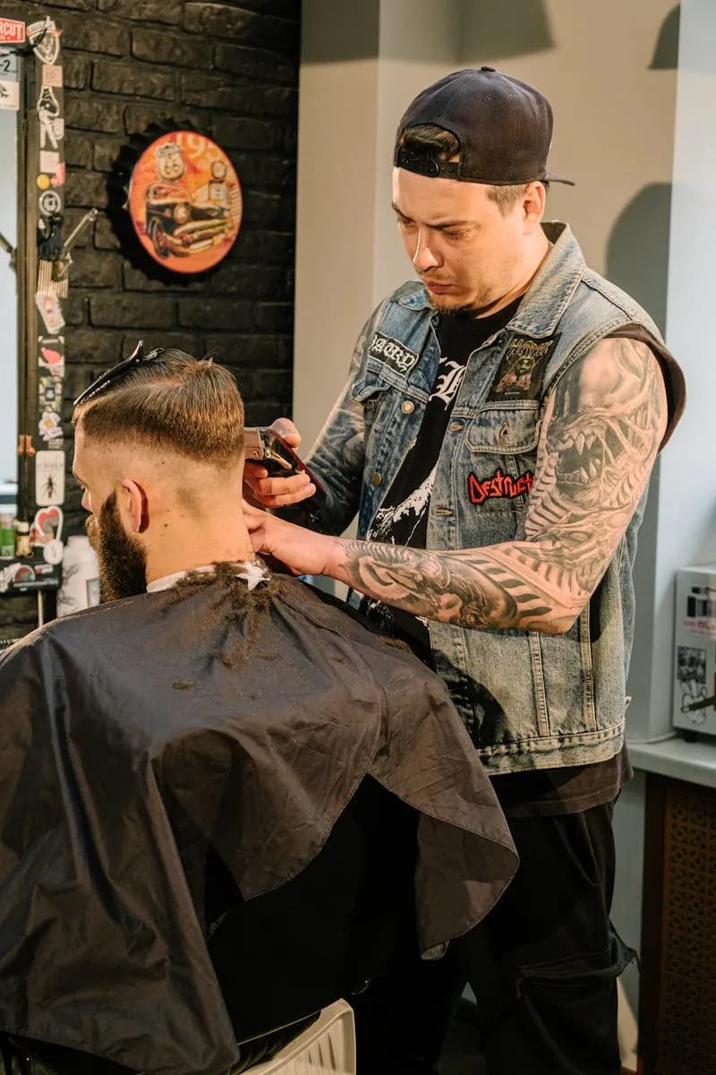 Barbero tatuado cortando en ambiente oscuro